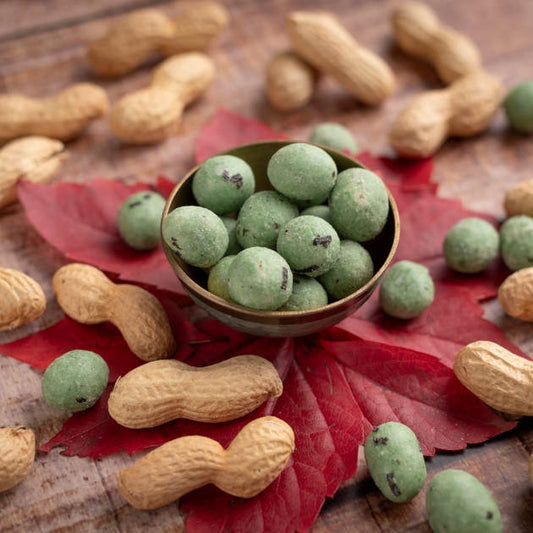 Erdnüsse mit Wasabi in Teigmantel von nussmart. Ansicht in Schale auf herbstliches Blatt platziert auf Holztisch mit Deko drumherum