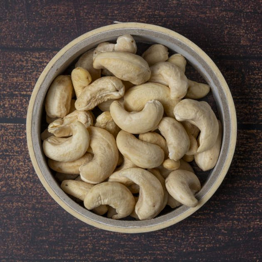 Cashewkerne von der Cote d'Ivoire - Elfenbeinküste. Transportwege sparen statt zur Verarbeitung nach Indien verschiffen!
Ansicht Kaschukerne in Schale von oben auf Holztischuntergrund