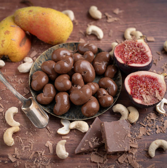 Schoko Cashew Vollmilch von nussmart. Cashew in Schale auf Holztisch. Dekoriert mit Cashew