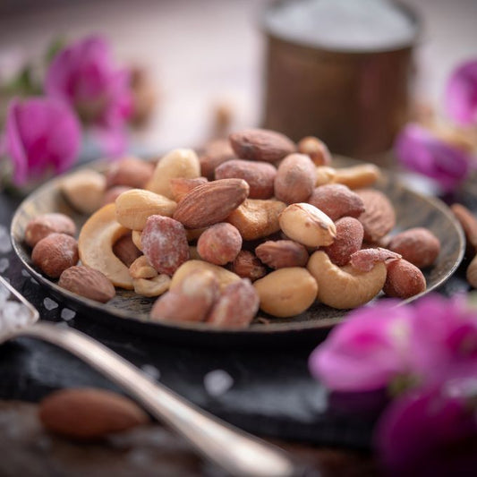 Salty Nut Mix von nussmart. Komposition von gerösteten und gesalzenen Nüssen. In Schale platziert mit Hintergrunddeko