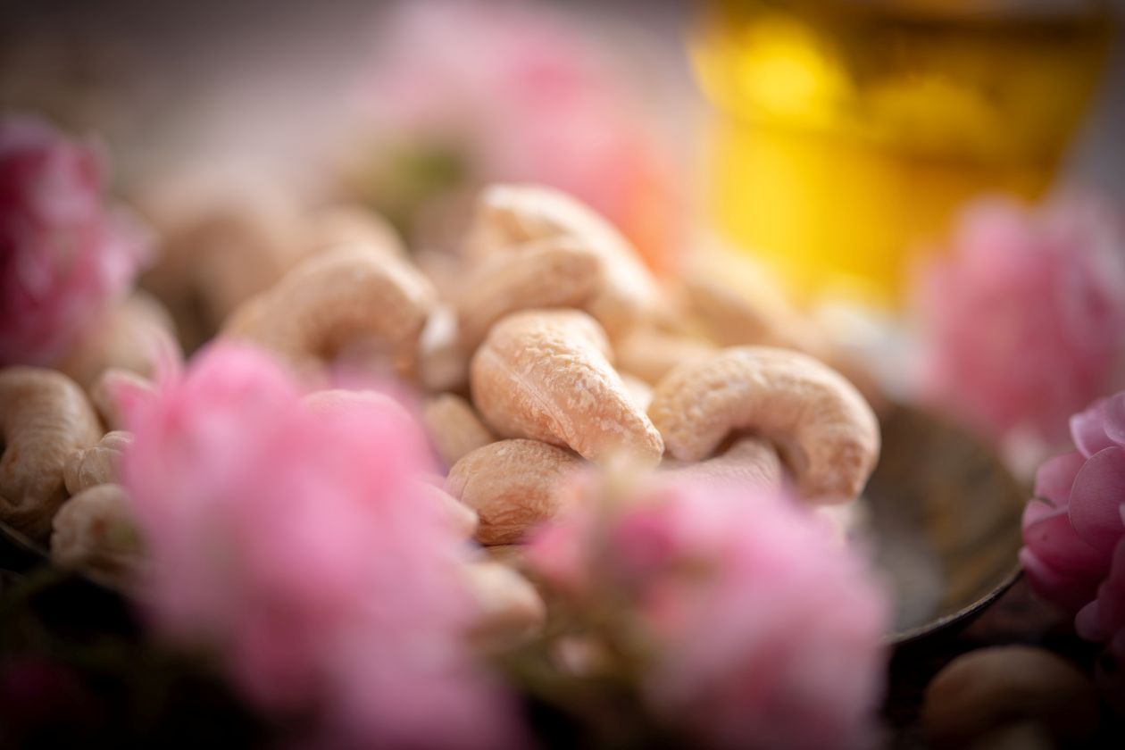 Detailansicht Cashewkerne trocken geröstet mit Deko rosa Blüten drumherum